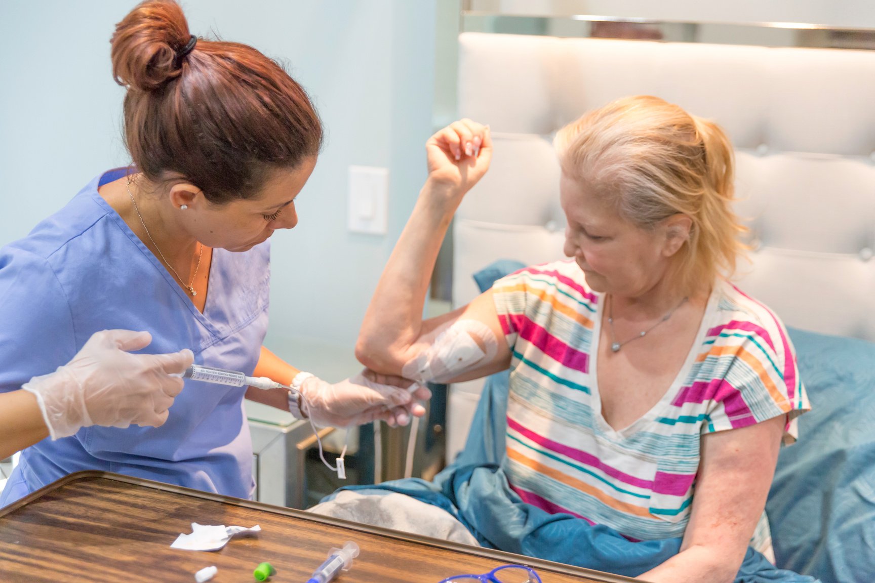 Home healthcare nurse flushing out the picc line of her female patient